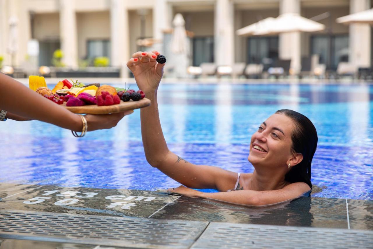 Triumph Luxury Hotel Kahire Dış mekan fotoğraf A woman being served fruit in a swimming pool